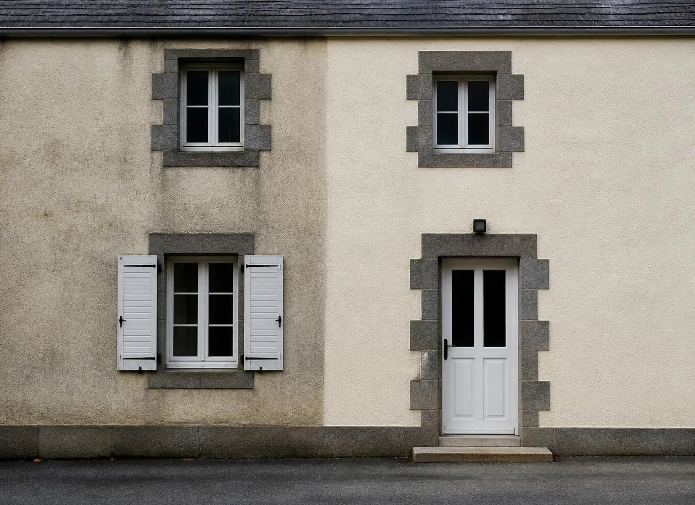 Façade enduite avec encadrements en pierre, une partie visiblement plus propre que l'autre